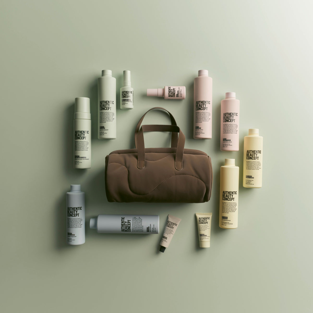 A brown fabric barrel bag arranged on a pale green background with multiple haircare bottles and tubes in blue, pink, yellow and green around it. The products show the visible brand name 'Authentic Beauty concept'.